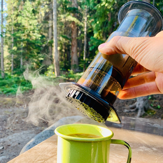 AeroPress making coffee in the woods with steam.